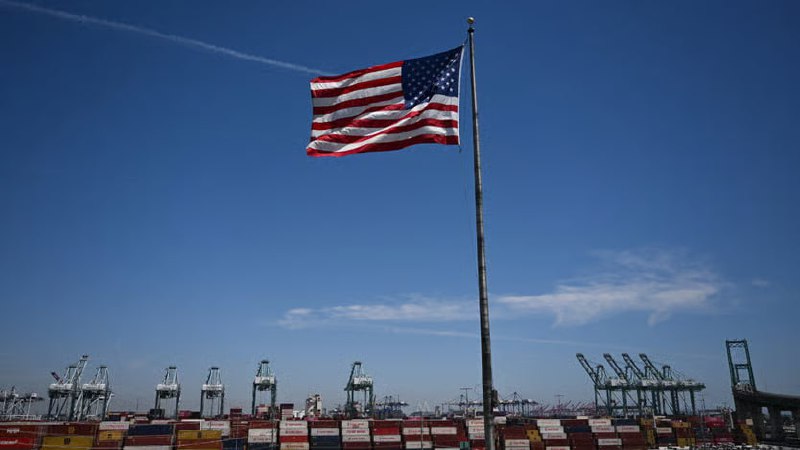Mark Carney descends the steps of a plane hidden by an American flag. 